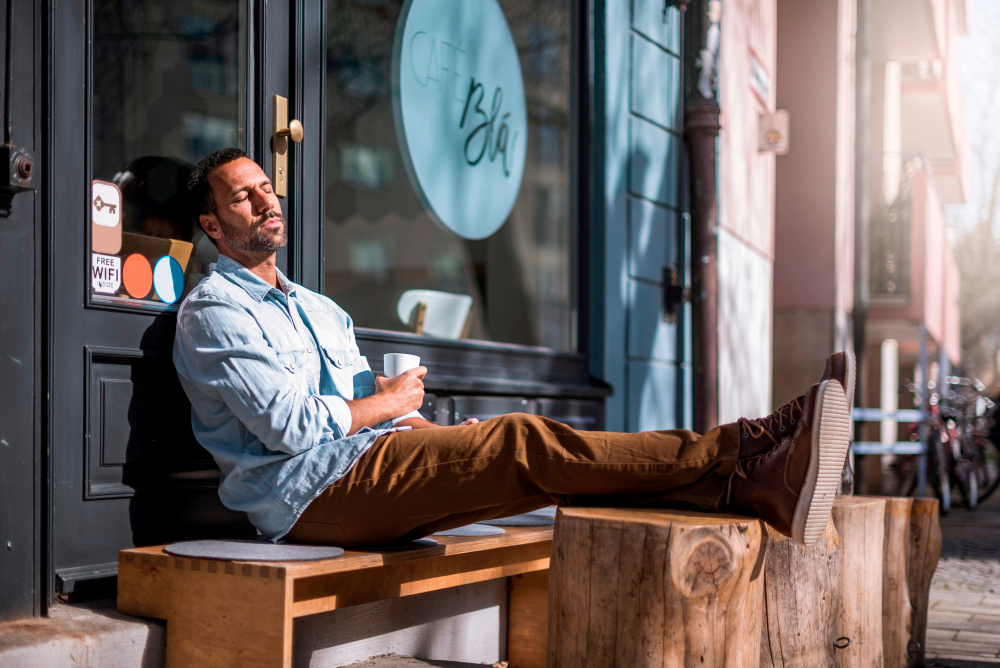 Relaxed man sitting outside a cafe enjoying the sunshine